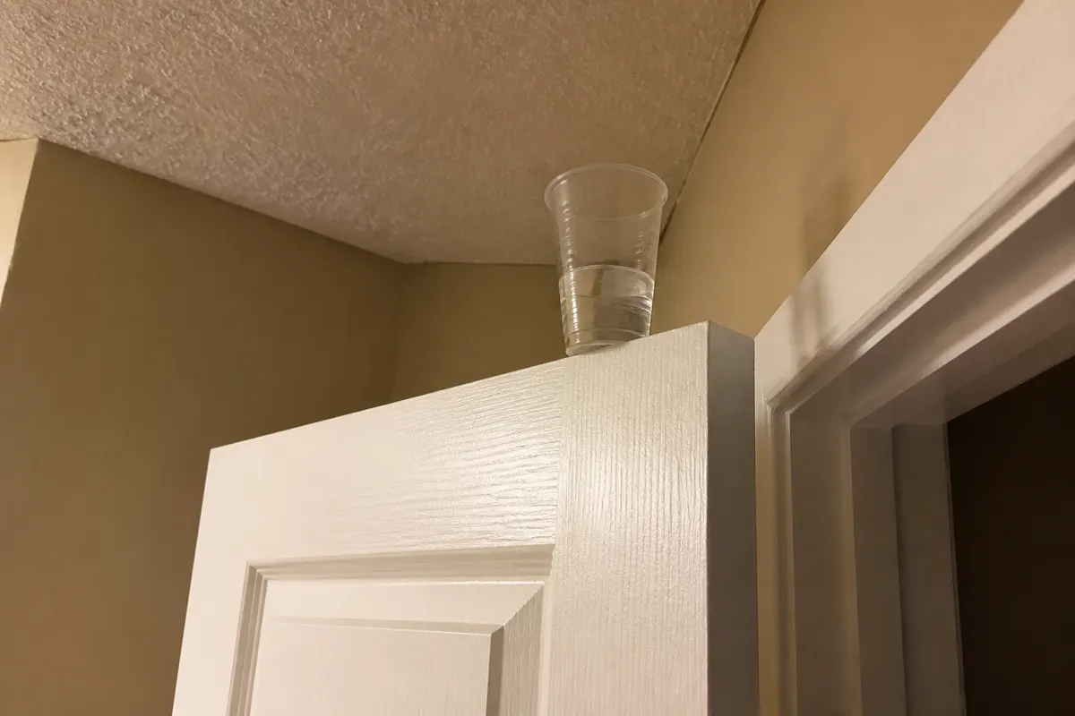A cup of water balanced on top of a door