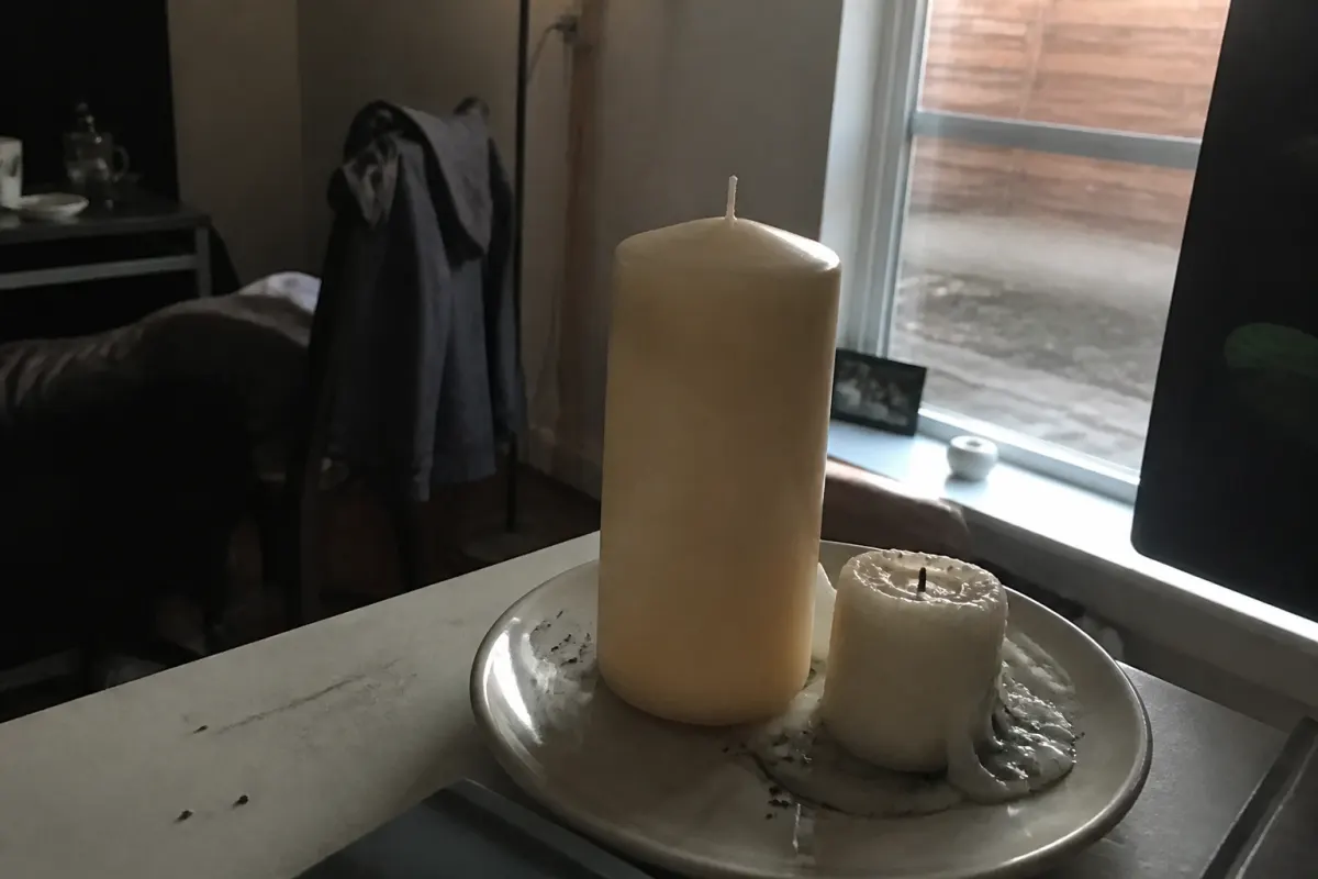 A tall candle beside a burnt-down stub