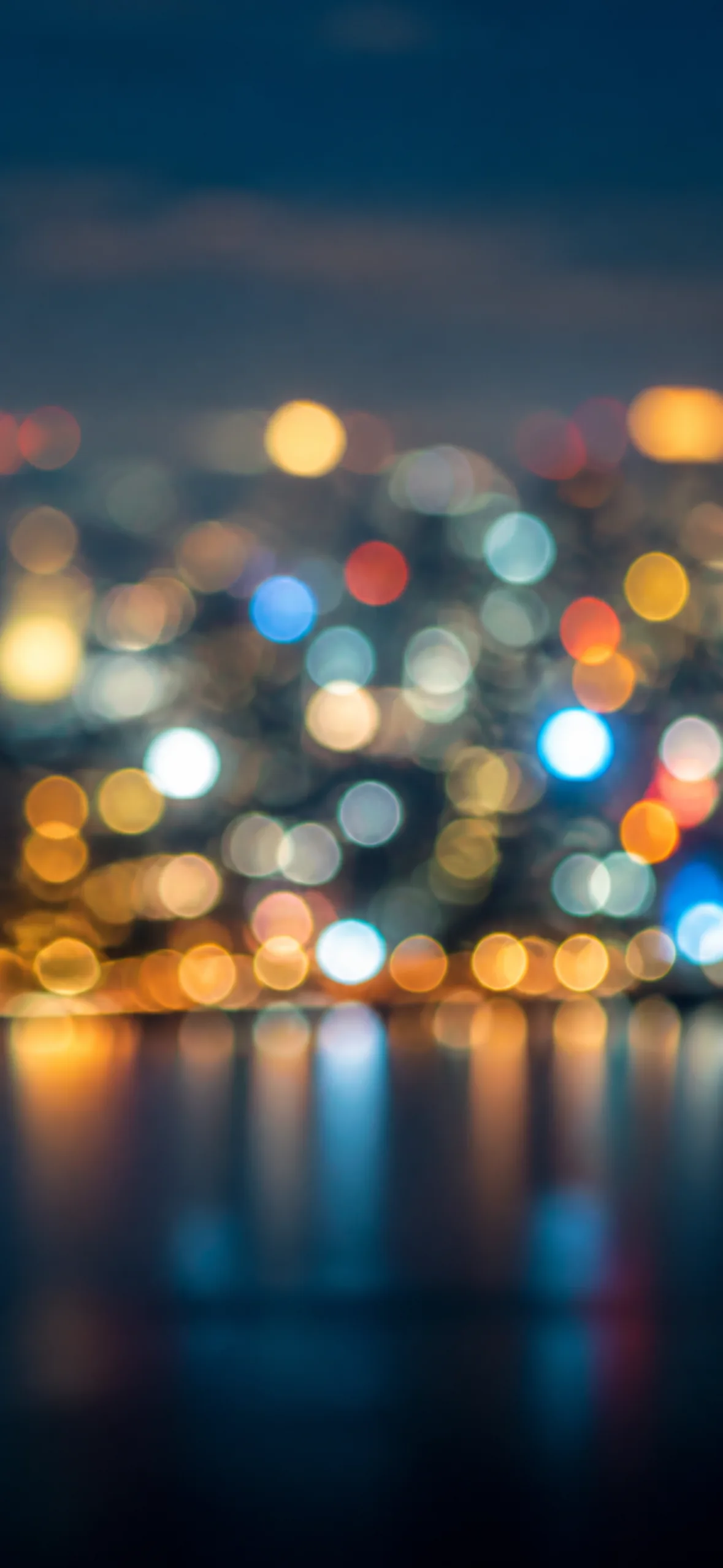iPhone lock screen wallpaper — city skyline thrown into soft bokeh at night