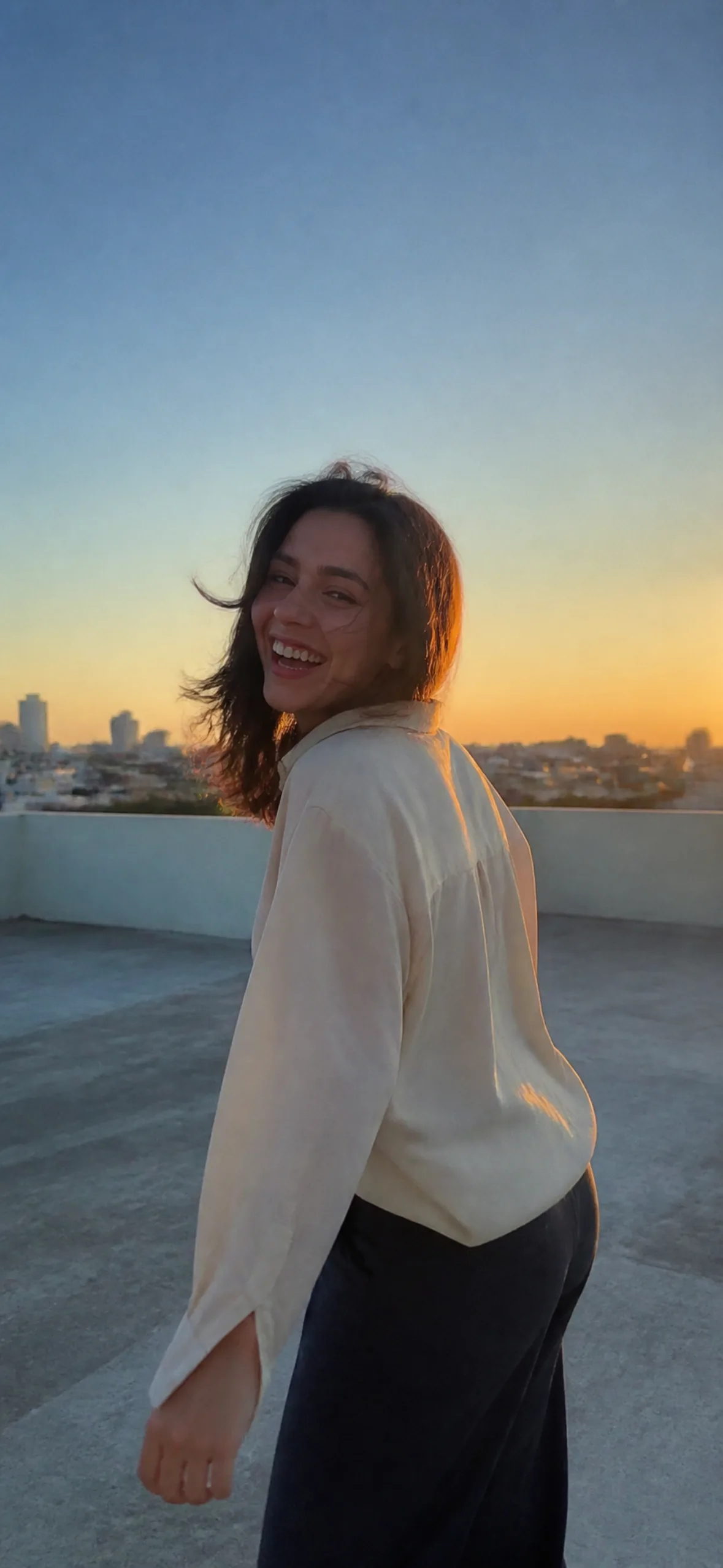 iPhone wallpaper — woman laughing on a rooftop at golden hour