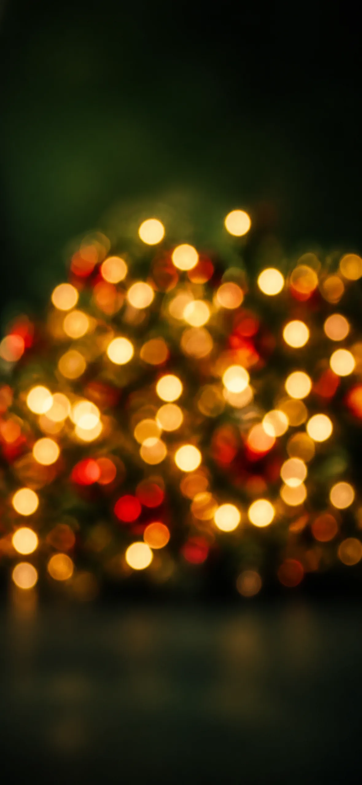 Phone wallpaper — a Christmas tree thrown into soft warm gold and red bokeh